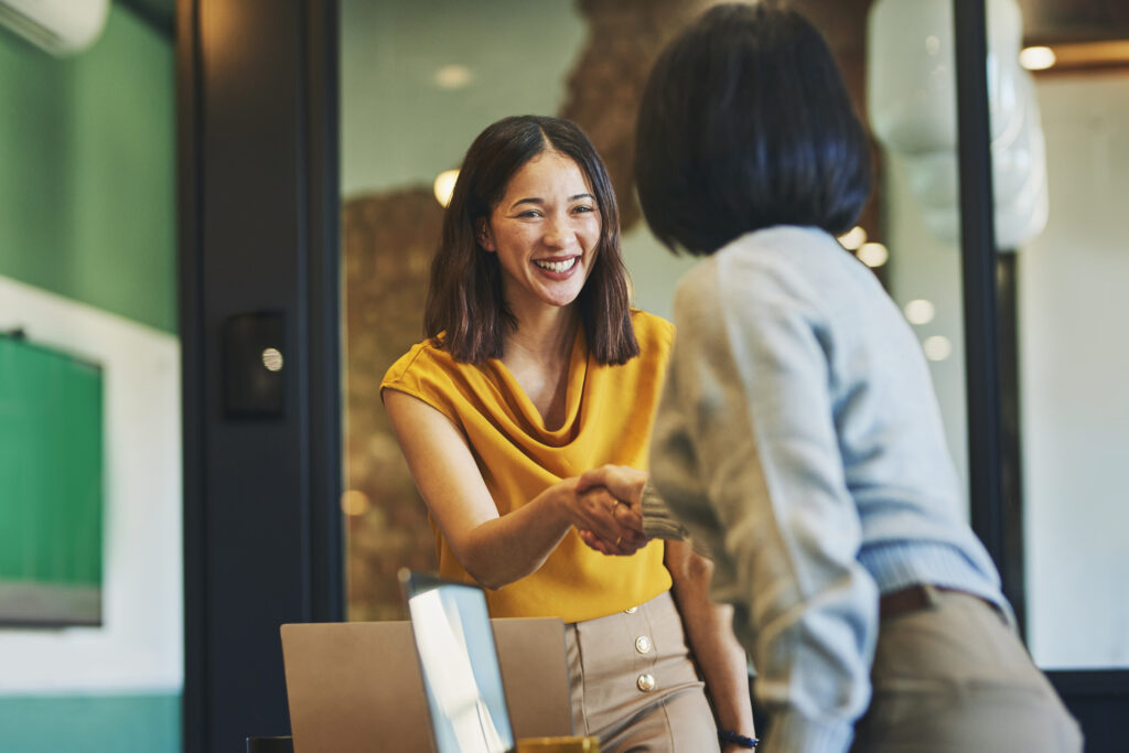 Cheerful businesswomen shaking hands in meeting room Businesswoman shaking hands with client and smiling cheerfully in meeting room