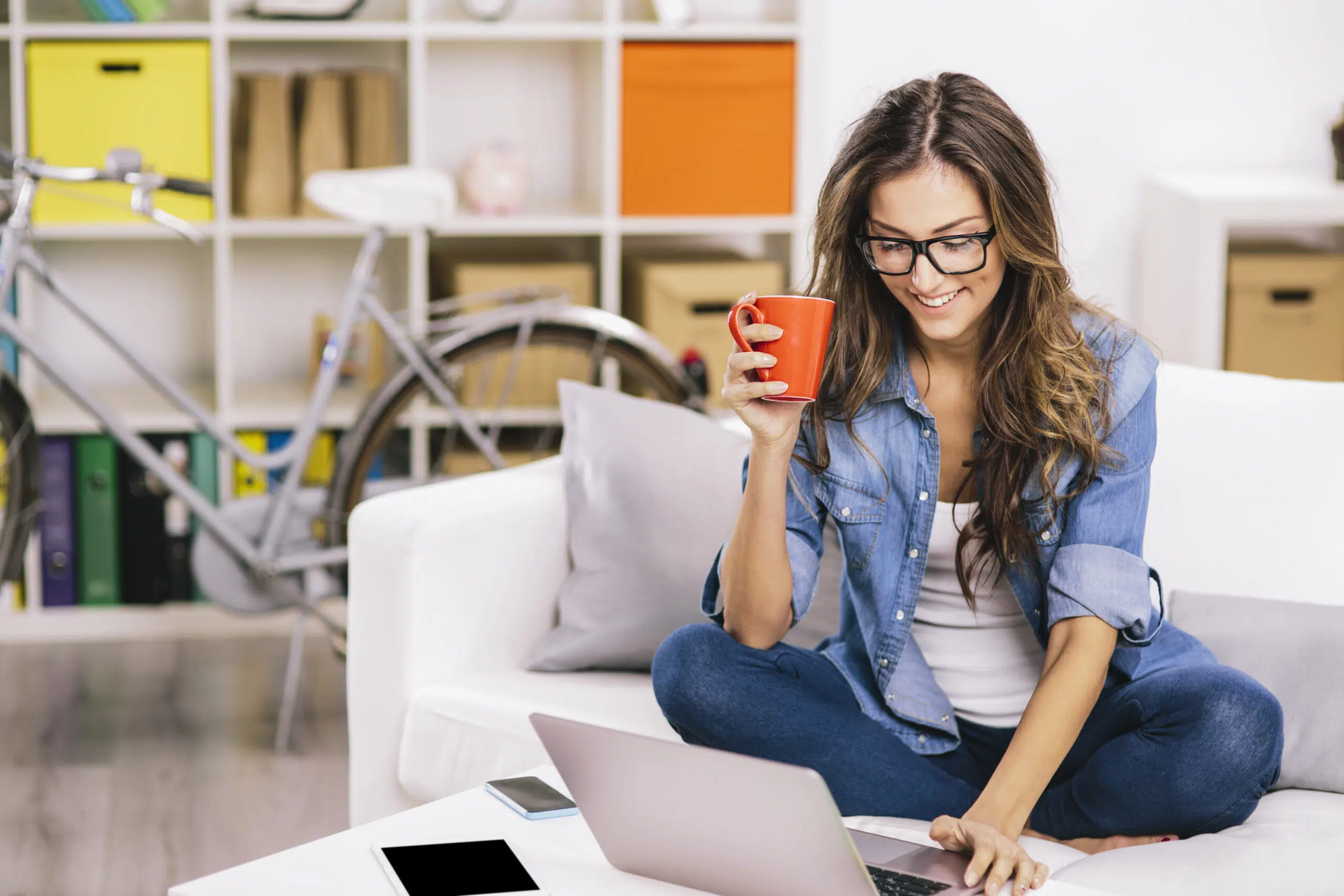 Woman sitting on a sofa and using a laptop.