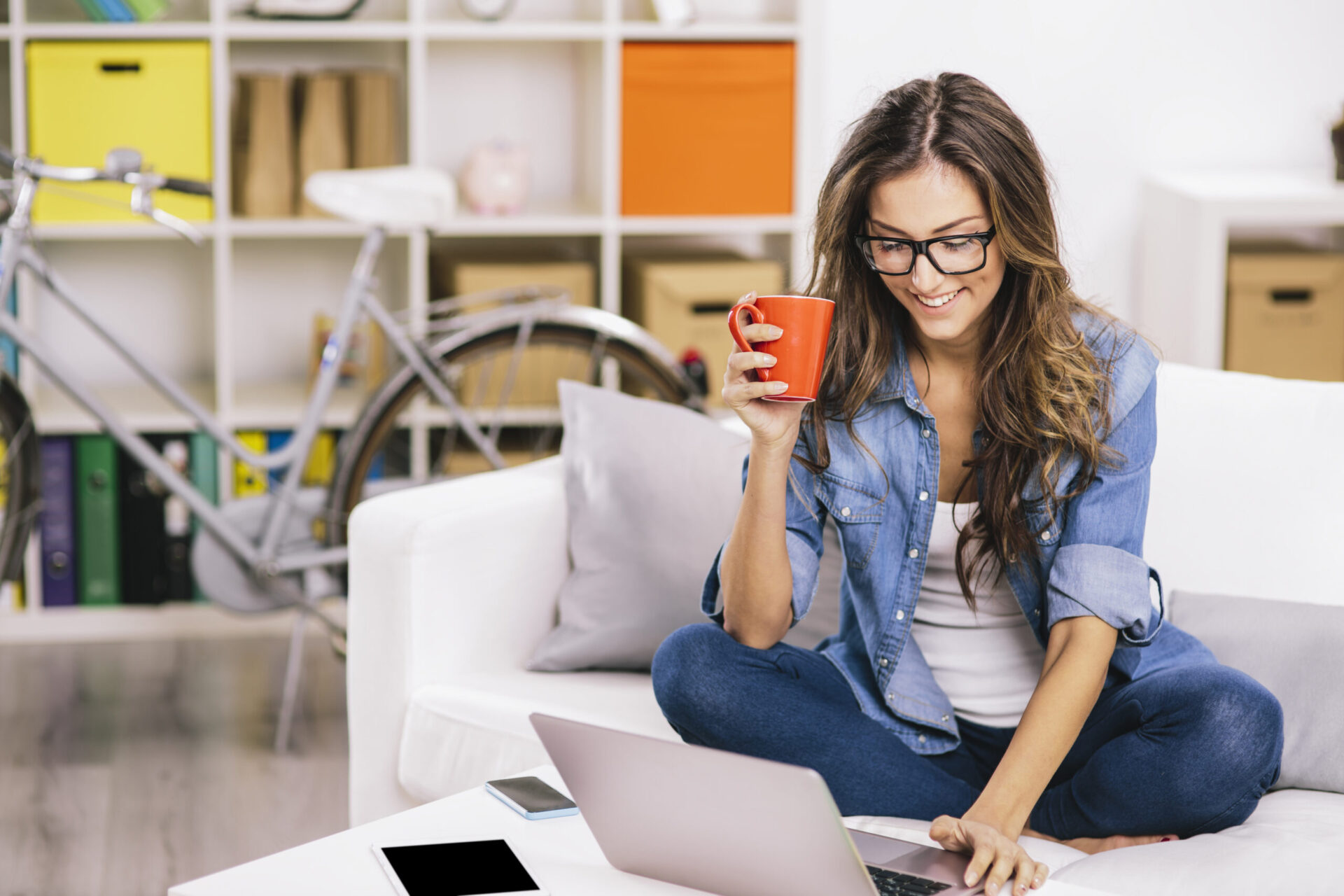 Woman sitting on a sofa and using a laptop.