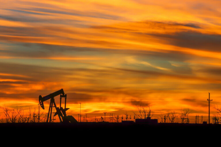 The natural beauty of a vibrant sunrise shines through the industries silhouette of the west Texas oil fields.