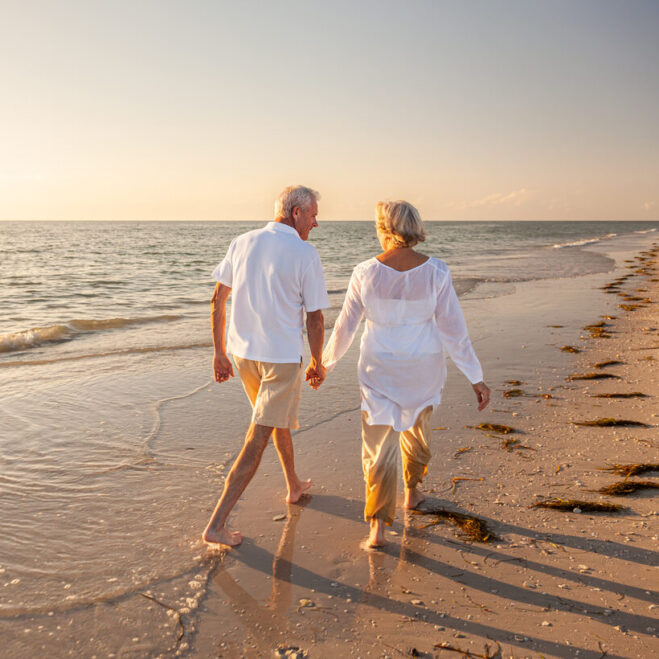 Happy Senior Old Retired Couple Walking Holding Hands on Beach at Sunset Discover retirement planning strategies to help preserve your wealth
