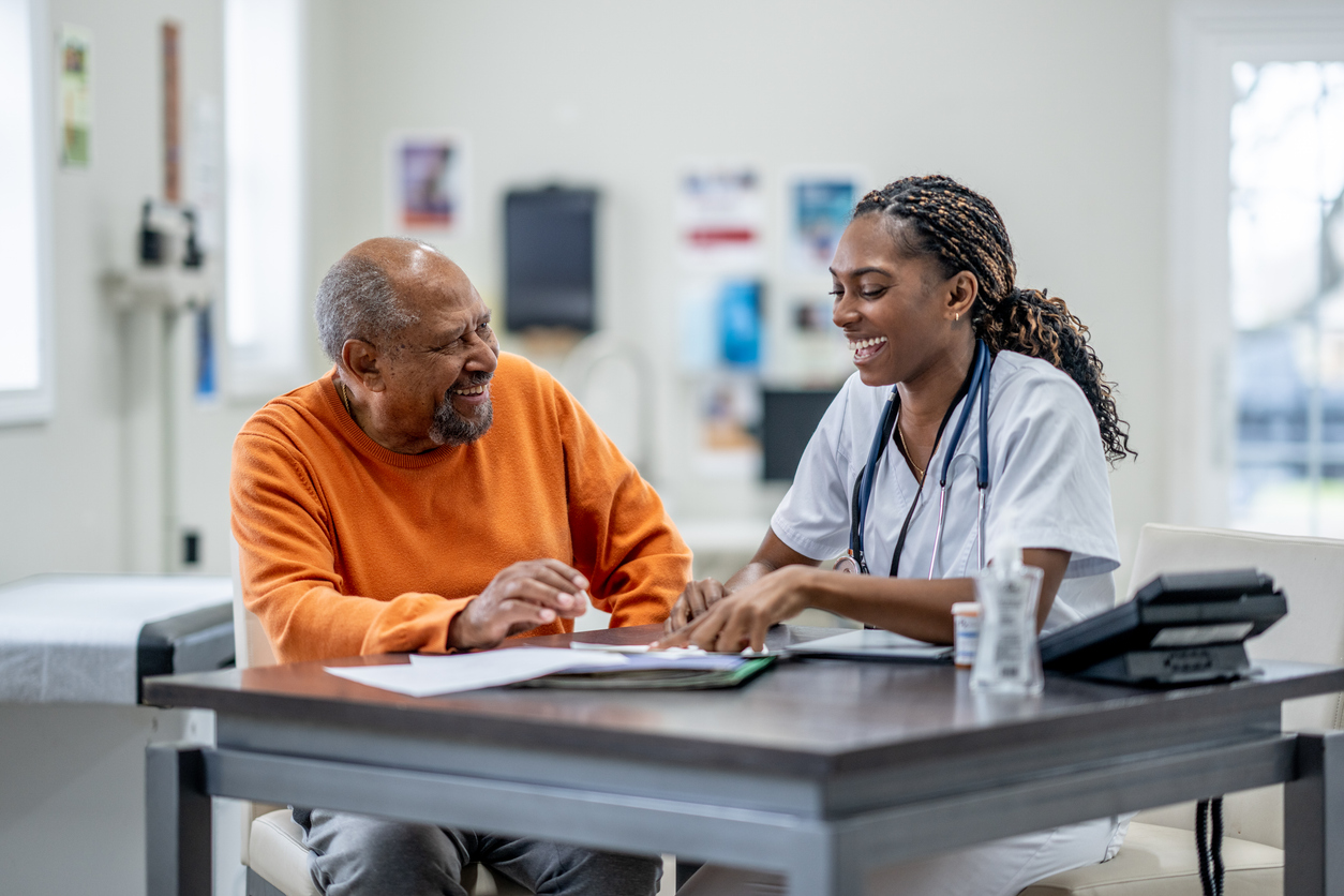 A female doctor of African decent, sits with a senior in her office as they review some recent test results together.